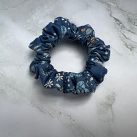Detailaufnahme des jeansblauen Baumwoll-Scrunchies mit floralem und Schmetterlingsprint – haarschonend und weich
