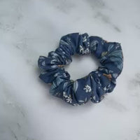 Detailaufnahme des jeansblauen Baumwoll-Scrunchies mit floralem und Schmetterlingsprint – haarschonend und weich