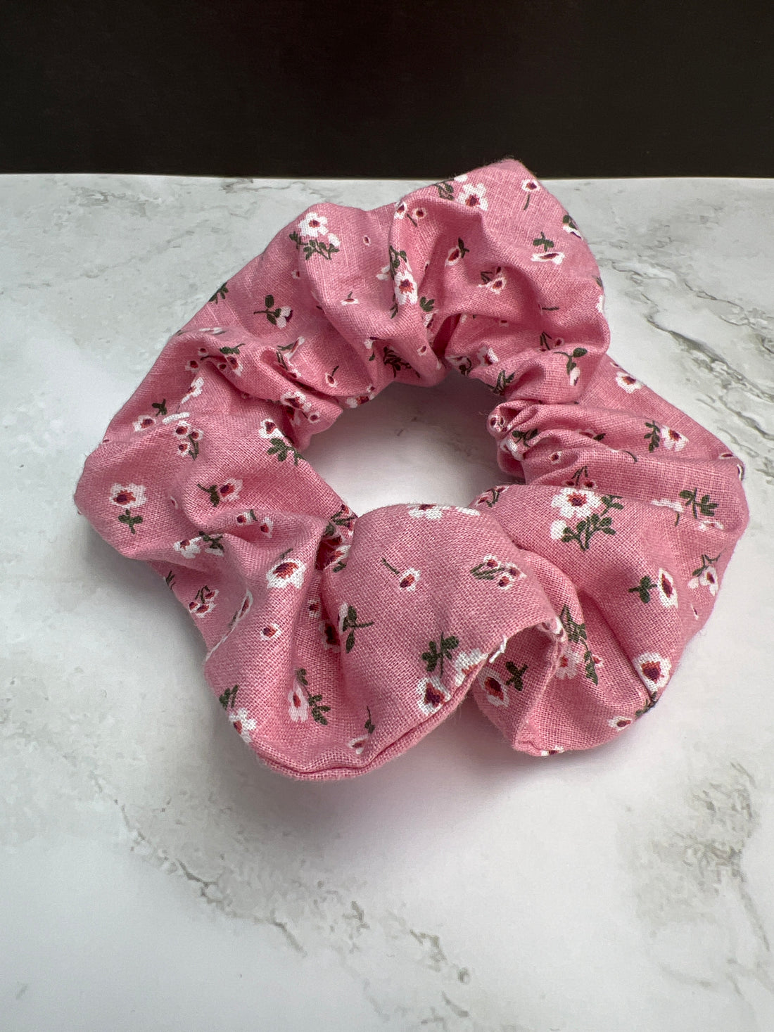 Detailaufnahme des handgemachten rosa Baumwoll-Scrunchies mit floralem Muster – haarschonend und weich