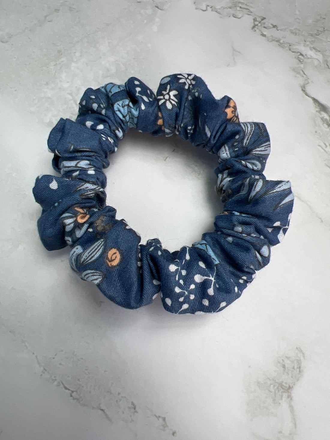 Nahaufnahme des Stoffes: jeansblaues Baumwoll-Scrunchie mit Blumen- und Schmetterlingsmuster – hochwertig verarbeitet