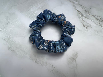 Detailaufnahme des jeansblauen Baumwoll-Scrunchies mit floralem und Schmetterlingsprint – haarschonend und weich