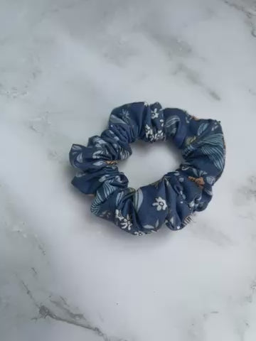 Detailaufnahme des jeansblauen Baumwoll-Scrunchies mit floralem und Schmetterlingsprint – haarschonend und weich
